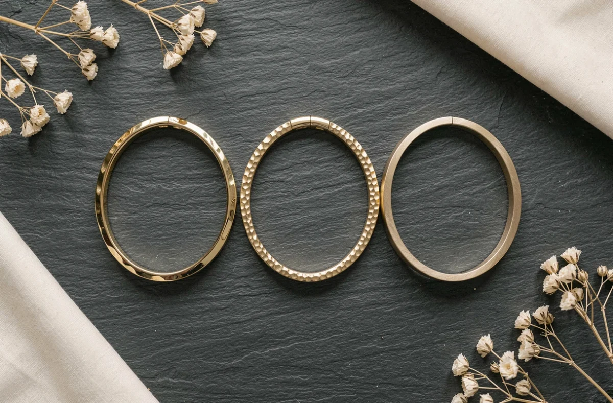Comparaison de trois bracelets en or aux finitions différentes : poli, martelé et brossé en flat lay