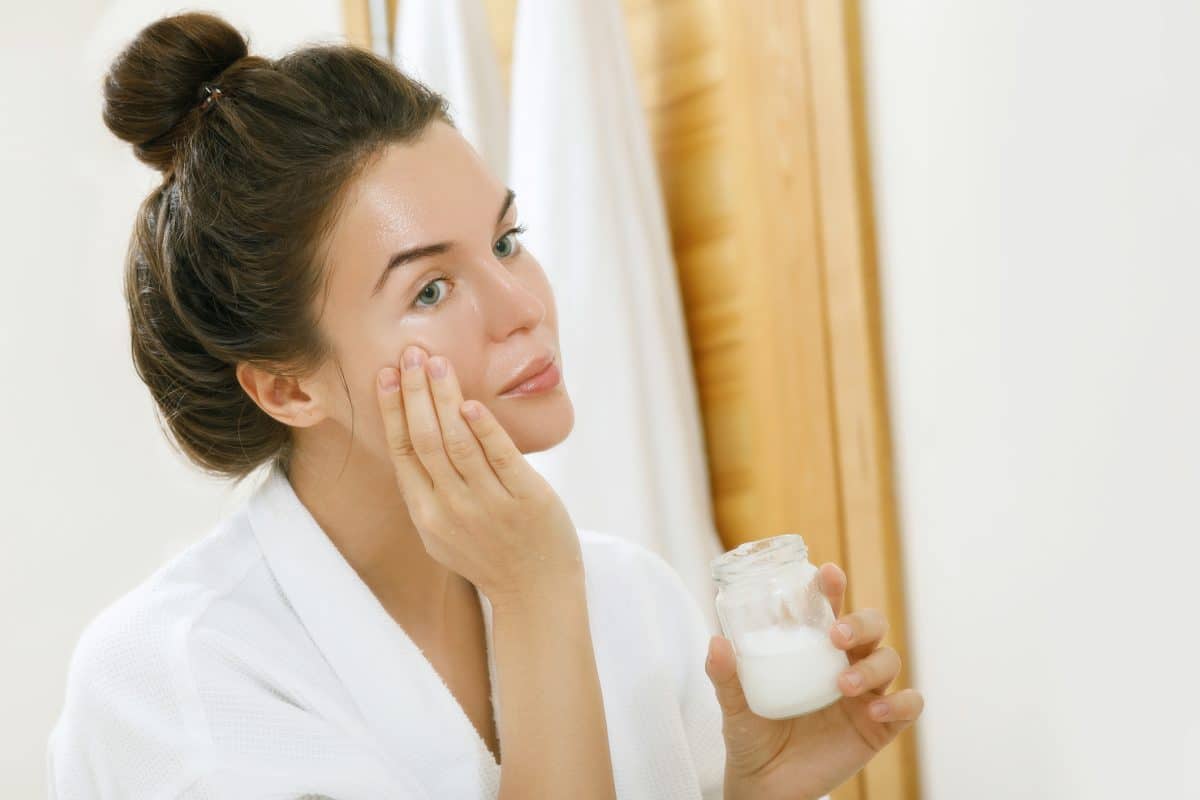 une femme appliquant de l'huile de coco sur son visage